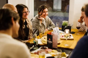 people sitting around a table and smiling, a picture from one of our past potlucks